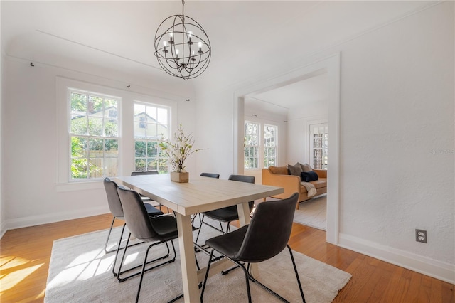 dining area with baseboards, light wood finished floors, and a chandelier