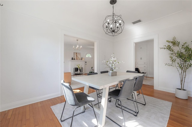 dining area with an inviting chandelier, baseboards, visible vents, and light wood finished floors