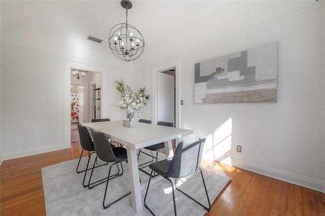 dining area with an inviting chandelier, wood finished floors, and baseboards