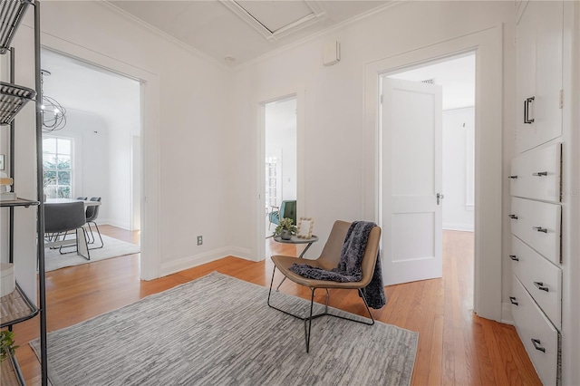 living area with light wood-type flooring, baseboards, and crown molding