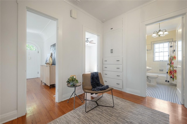 sitting room with an inviting chandelier, crown molding, wood finished floors, and baseboards