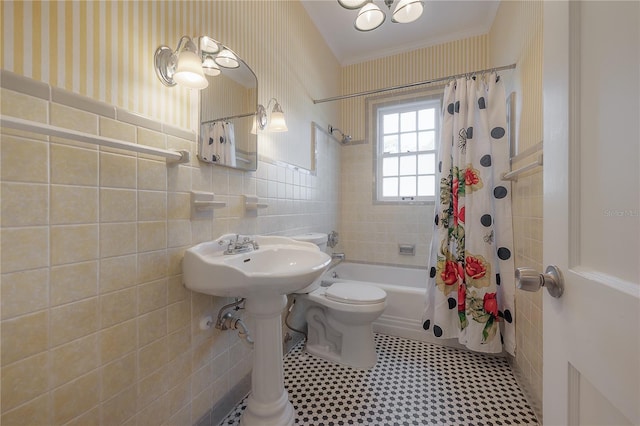 bathroom with shower / bath combo with shower curtain, a wainscoted wall, wallpapered walls, and tile walls