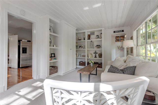 carpeted living area featuring built in features and wood ceiling