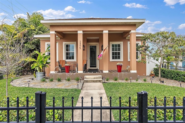 view of front facade with a front lawn, covered porch, a fenced front yard, and stucco siding