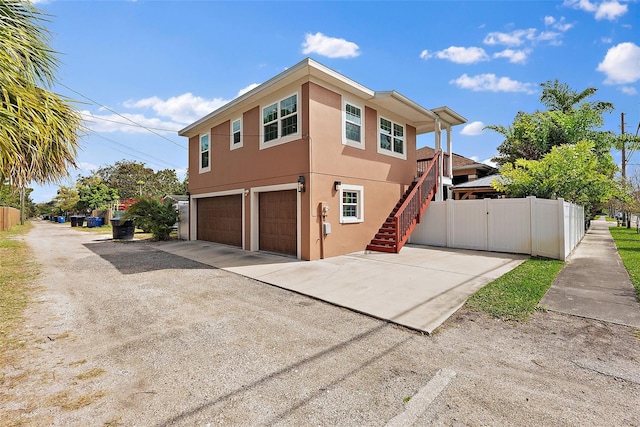 view of side of home featuring a gate, fence, an attached garage, and stucco siding