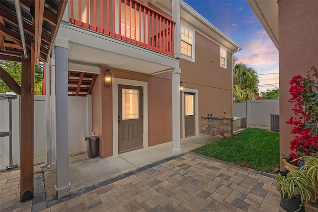 exterior space featuring a balcony, fence, central AC, and stucco siding