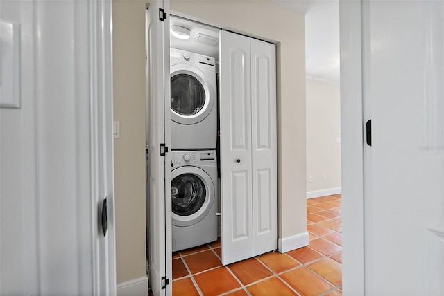 laundry room with baseboards, stacked washer and clothes dryer, light tile patterned flooring, and laundry area