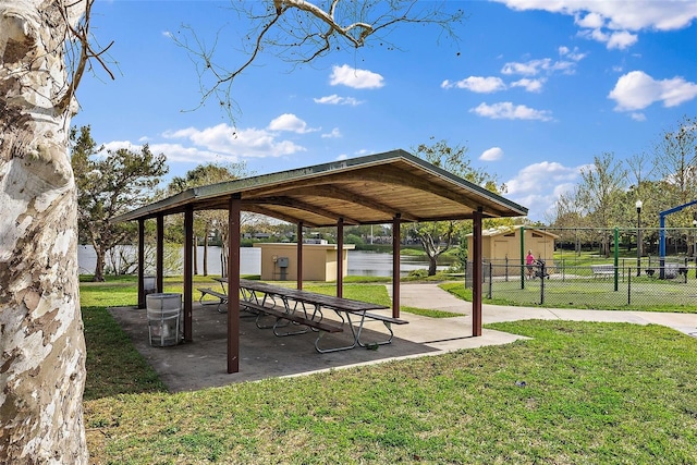 view of community featuring a lawn, an outdoor structure, and fence