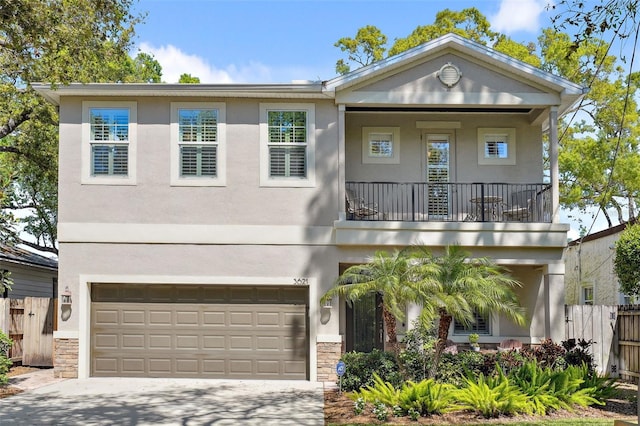 view of front of house featuring concrete driveway, a balcony, fence, and stucco siding