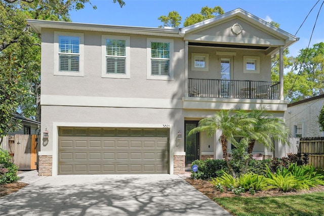 view of front of home with fence, concrete driveway, stucco siding, a balcony, and stone siding