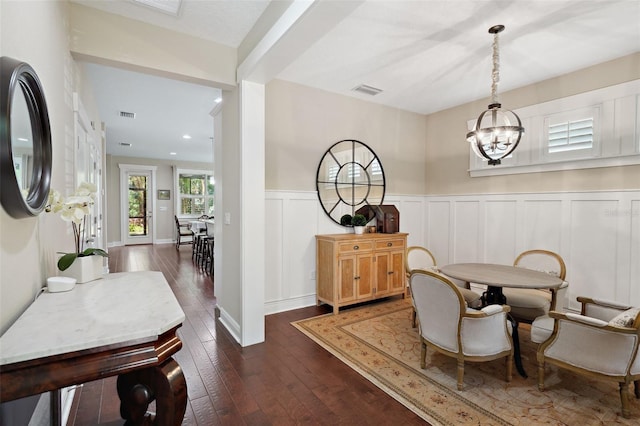 interior space featuring a chandelier, visible vents, dark wood finished floors, and a wainscoted wall