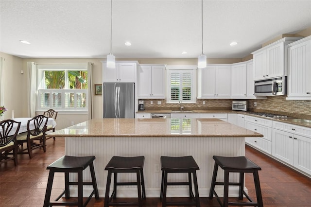 kitchen featuring a sink, stainless steel appliances, a kitchen breakfast bar, and a kitchen island