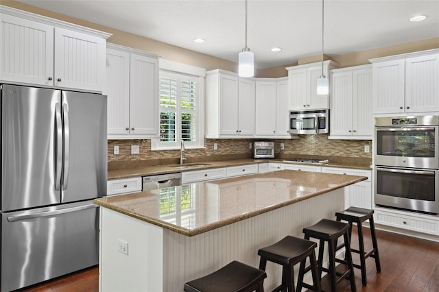 kitchen featuring backsplash, a center island, a breakfast bar, stainless steel appliances, and a sink