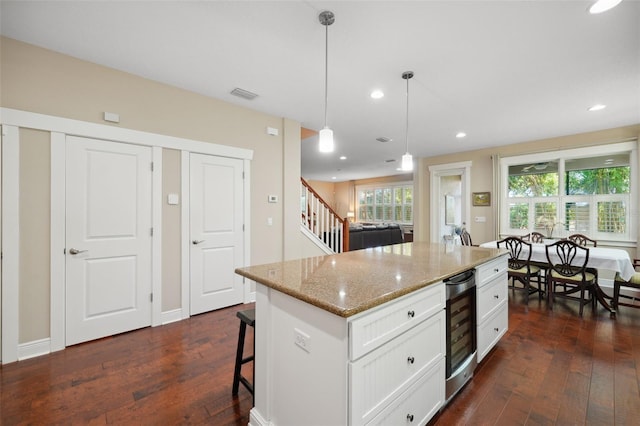 kitchen featuring beverage cooler, visible vents, dark wood finished floors, and white cabinetry