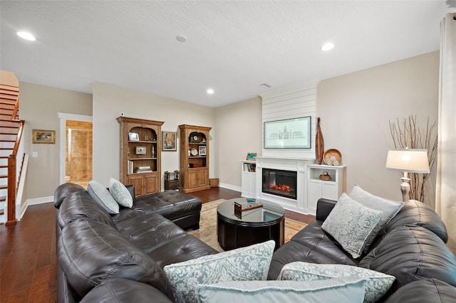 living room featuring dark wood-style floors, a glass covered fireplace, recessed lighting, and baseboards