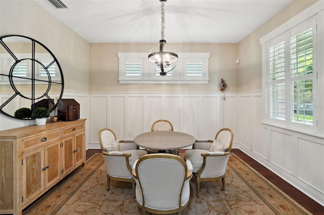 dining space featuring visible vents, wood finished floors, wainscoting, and a chandelier