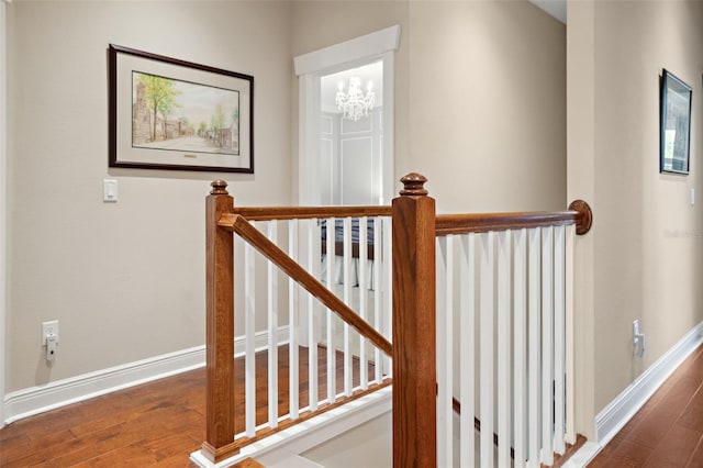 staircase featuring baseboards, a notable chandelier, and wood finished floors