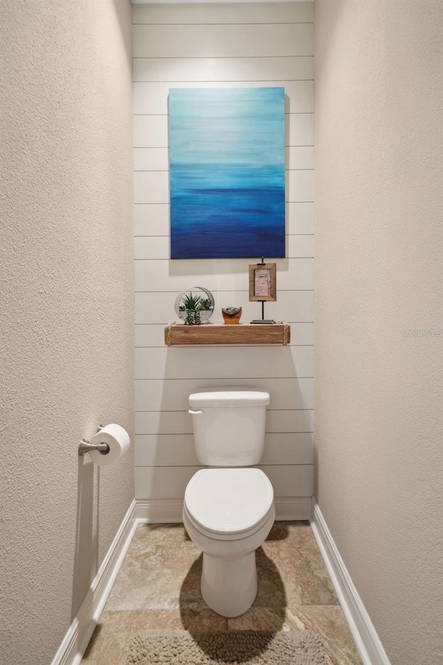 bathroom featuring toilet, baseboards, and a textured wall