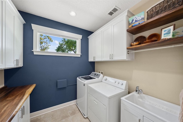 washroom featuring visible vents, washer and dryer, cabinet space, light tile patterned floors, and baseboards