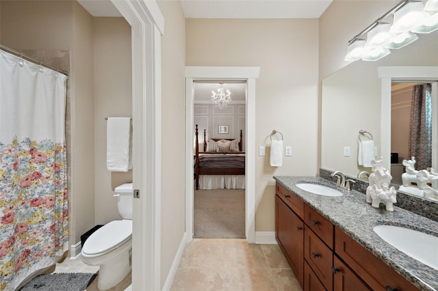 bathroom featuring a sink, toilet, a chandelier, and double vanity