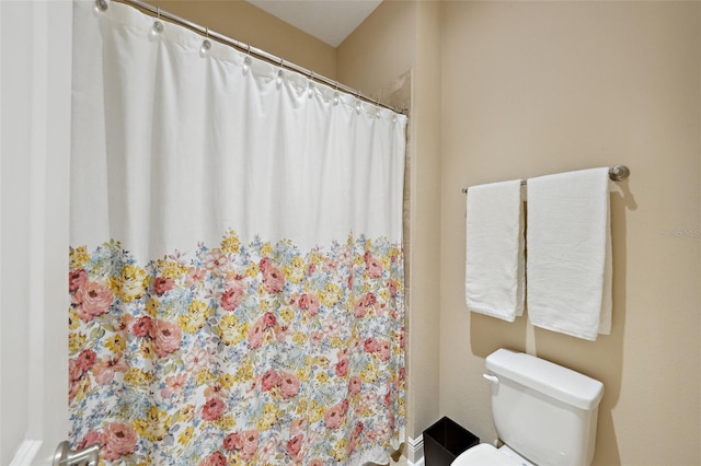 bathroom with a shower with shower curtain and toilet