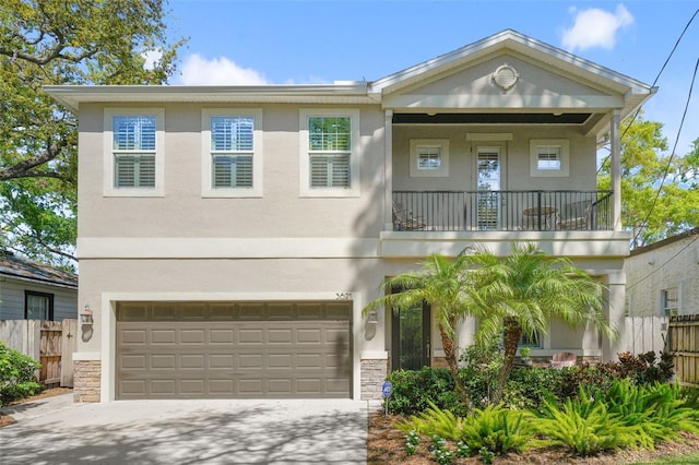 view of front of property with stucco siding, a balcony, and fence