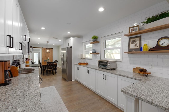 kitchen with light wood finished floors, open shelves, stainless steel fridge with ice dispenser, white cabinets, and tasteful backsplash