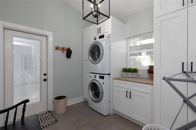 laundry area featuring baseboards, cabinet space, and stacked washing maching and dryer