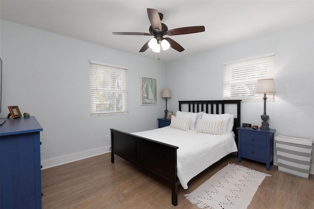 bedroom featuring baseboards, wood finished floors, and a ceiling fan