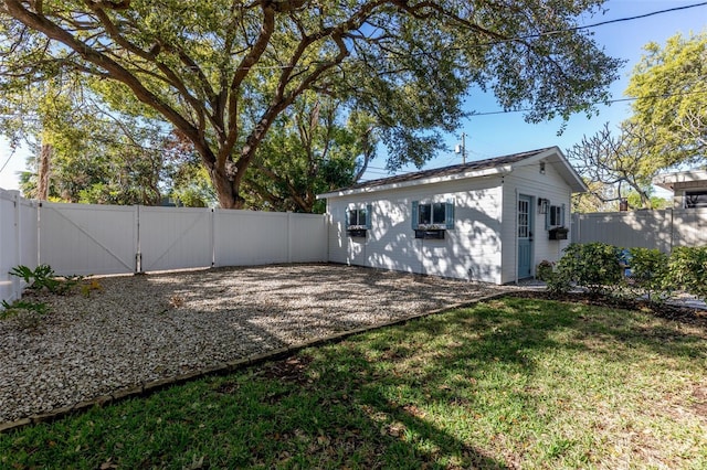 back of house with a yard, an outbuilding, a fenced backyard, and a gate