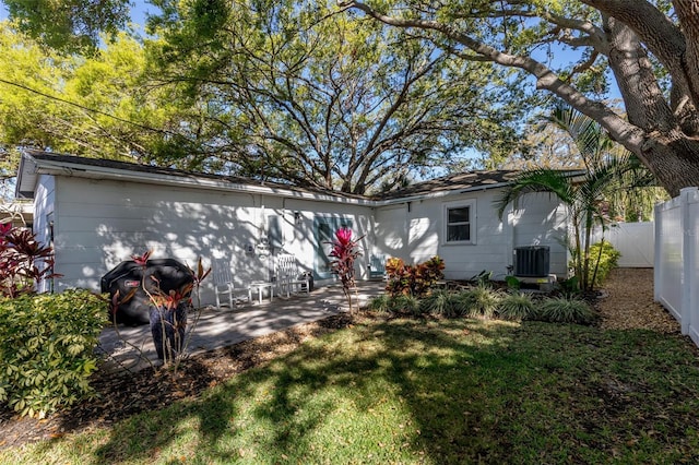 rear view of house featuring a patio area, central air condition unit, fence, and a lawn