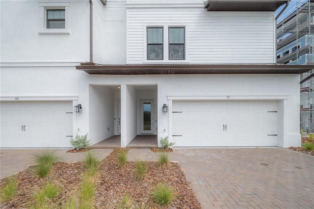 view of front of home with stucco siding, an attached garage, and decorative driveway