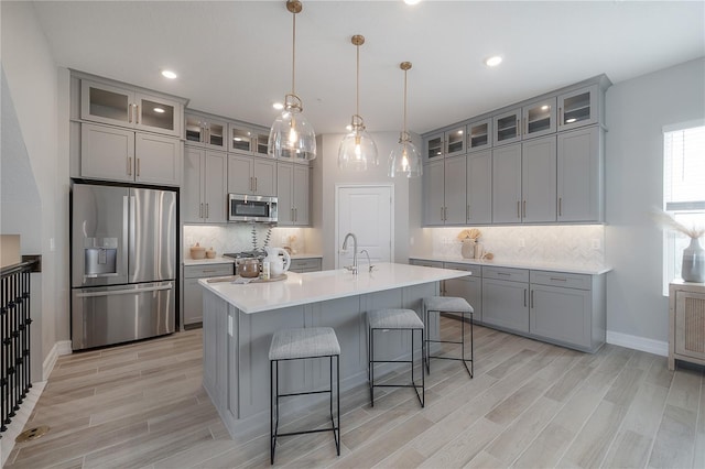 kitchen with appliances with stainless steel finishes, a kitchen bar, and gray cabinetry