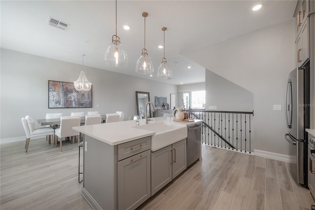 kitchen with visible vents, gray cabinets, appliances with stainless steel finishes, light wood-style flooring, and a sink