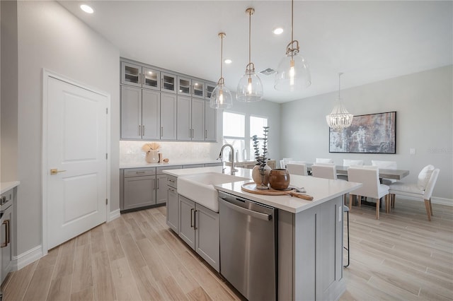 kitchen with stainless steel dishwasher, light wood-style flooring, gray cabinets, and light countertops