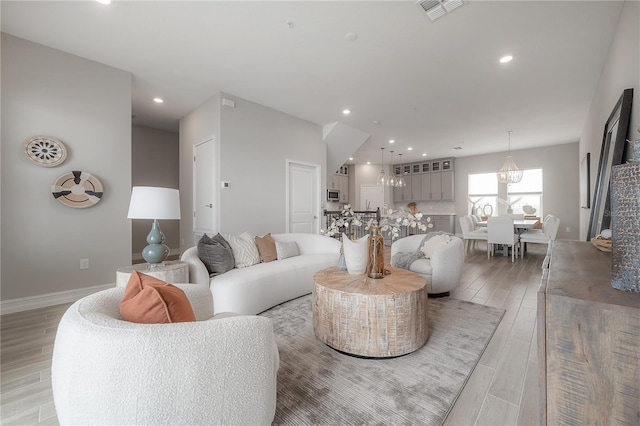 living area featuring baseboards, recessed lighting, visible vents, and light wood-type flooring