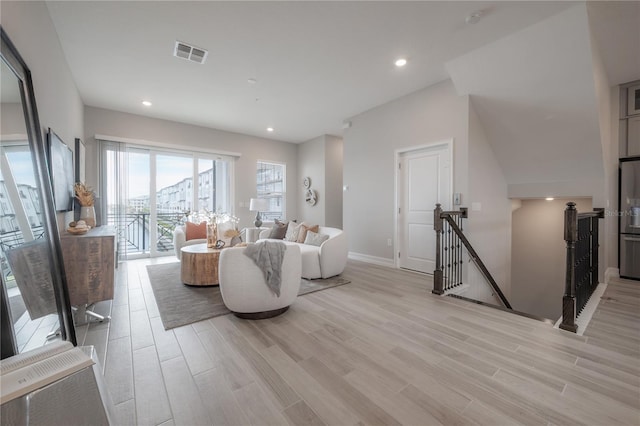 living room featuring light wood-type flooring, visible vents, baseboards, and recessed lighting