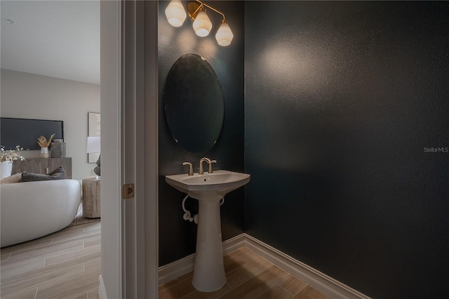 bathroom featuring wood finish floors, baseboards, and a freestanding bath