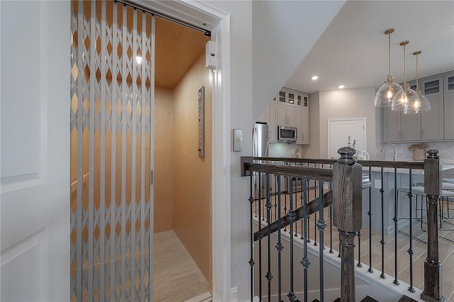 interior space featuring decorative backsplash, elevator, recessed lighting, and appliances with stainless steel finishes