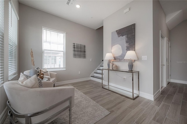 sitting room with stairs, visible vents, baseboards, and wood tiled floor