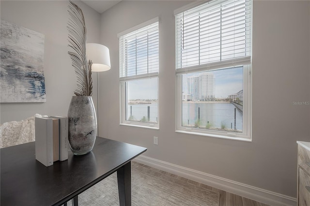 home office with baseboards and a water view