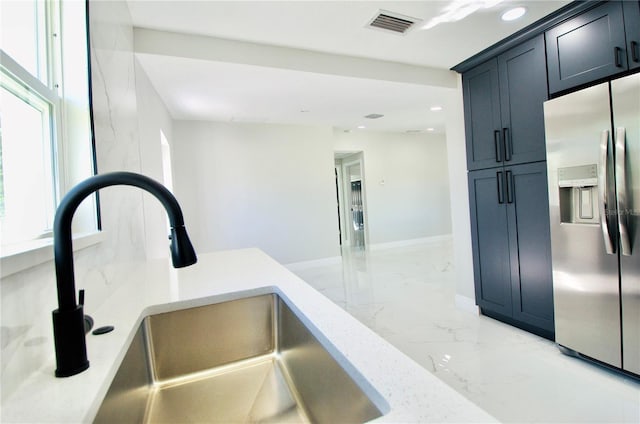 kitchen with visible vents, light stone countertops, stainless steel fridge with ice dispenser, marble finish floor, and a sink