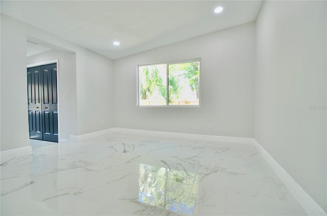 spare room with recessed lighting, marble finish floor, and baseboards