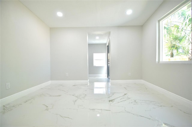 empty room featuring recessed lighting, marble finish floor, and baseboards