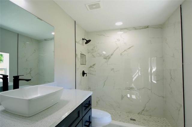 bathroom featuring visible vents, toilet, recessed lighting, a marble finish shower, and vanity