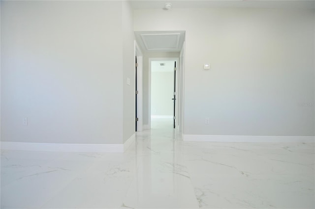 corridor with attic access, baseboards, and marble finish floor