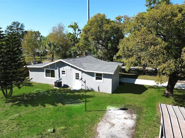 exterior space featuring a front lawn, stucco siding, and a shingled roof