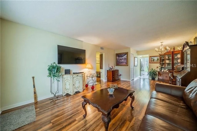 living room with a chandelier, baseboards, visible vents, and wood finished floors