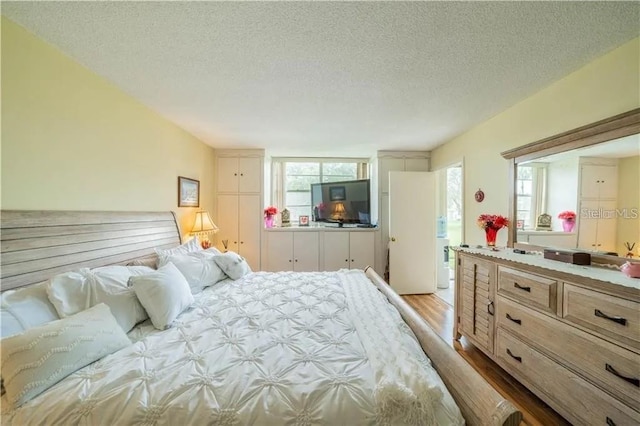 bedroom featuring multiple windows, a textured ceiling, and wood finished floors