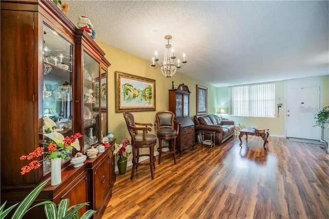 living room featuring a notable chandelier, wood finished floors, and a textured ceiling